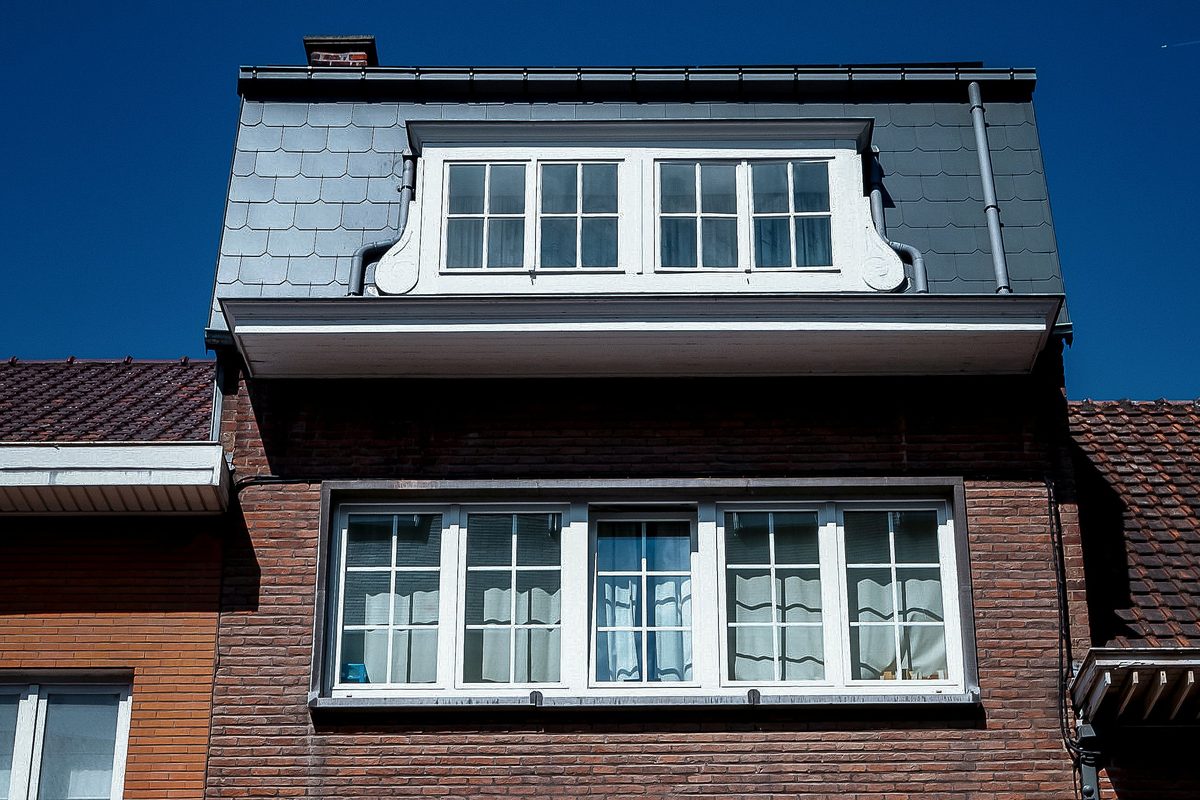 Rijwoning met een brede dakkapel met witte ramen in een leien dak