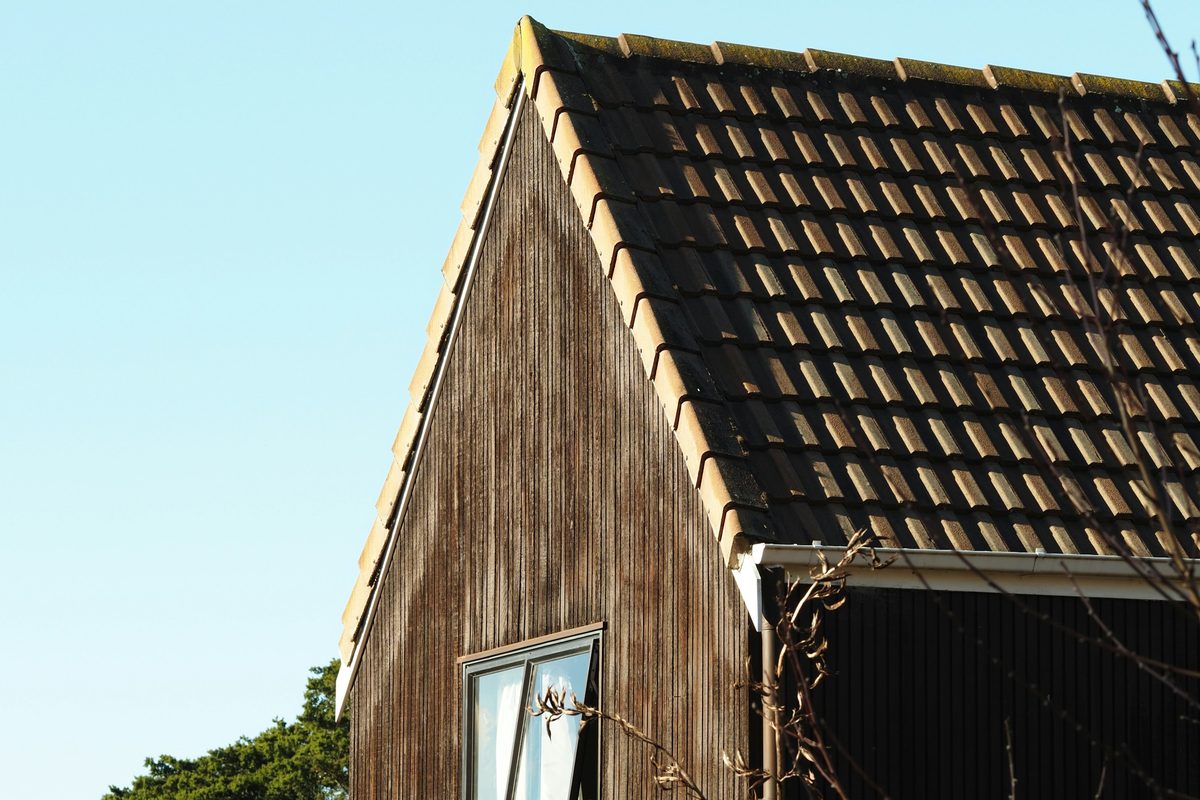 Topgevel bekleed met verticale houten planken onder een pannendak